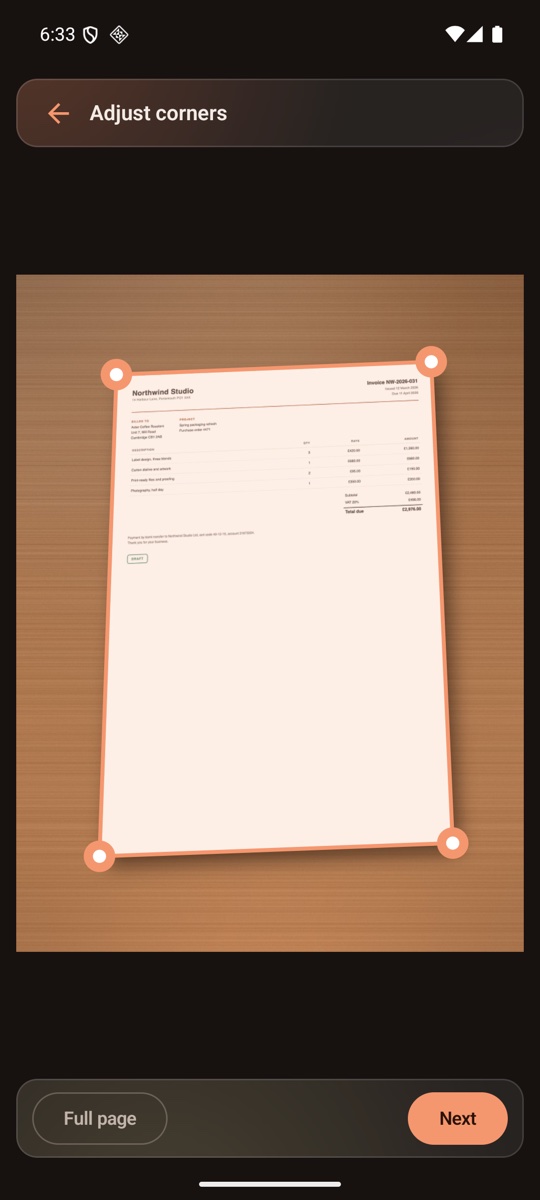 DocFort Lite scan tool showing an invoice on a wooden desk with four draggable corner handles around the page